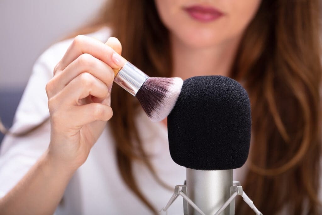 Do ASMR YouTubers make money? An ASMR YouTuber rubs a makeup brush over the foam cover of a podcasting microphone